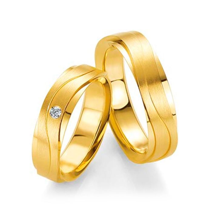 Обручальные кольца с плавными линиями и бриллиантом на кольце невесты
